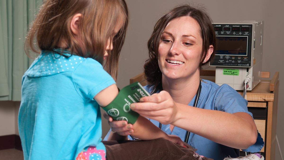 A pre-health student puts a blood pressure cuff on a patient.