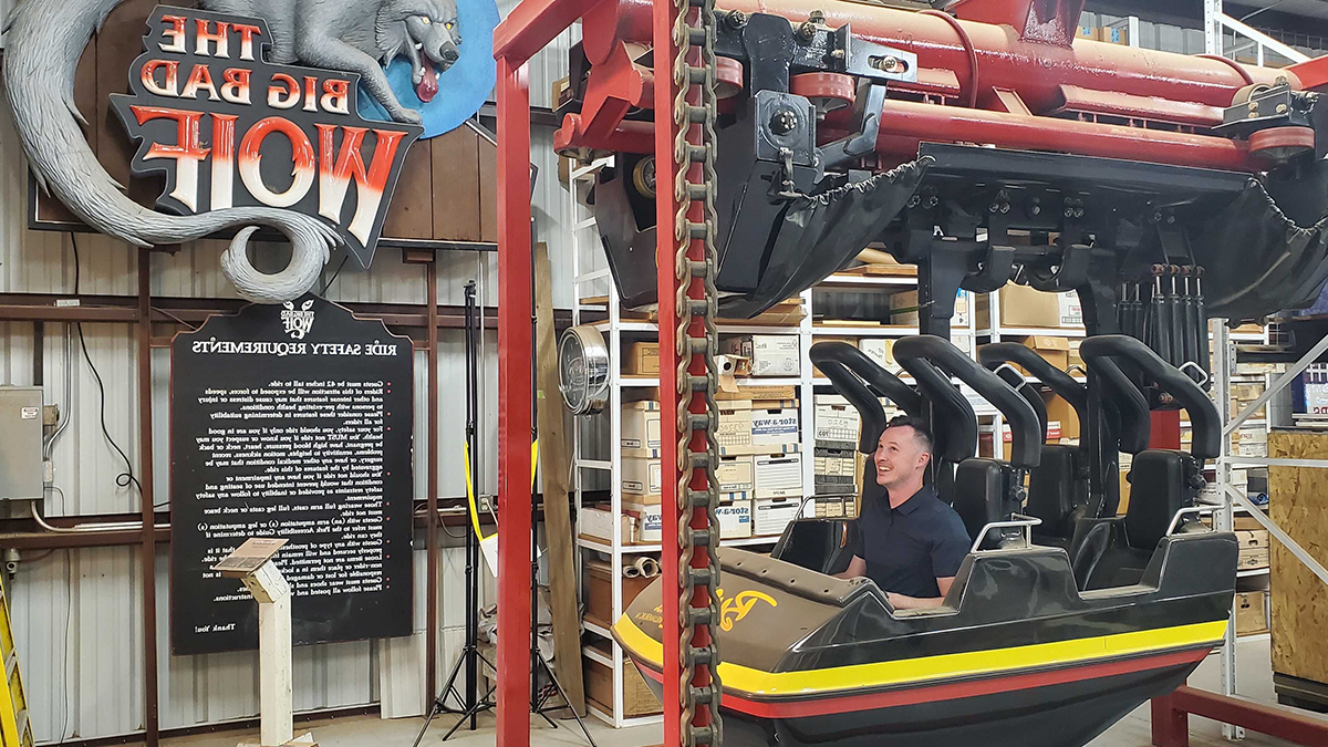 Man sits in black roller coaster train cart. 